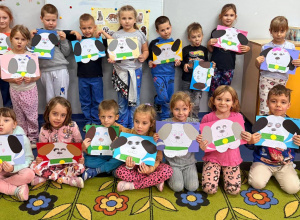 Dzieci z oddziału przedszkolnego trzymają w rękach papierowego pieska stworzonego z kolorowych wycinanek.