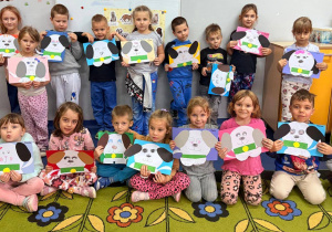 Dzieci z oddziału przedszkolnego trzymają w rękach papierowego pieska stworzonego z kolorowych wycinanek.