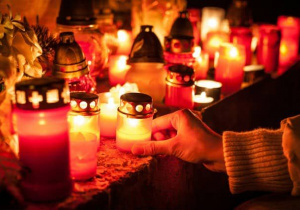 Zapalone znicze ustawione na kamiennej powierzchni.