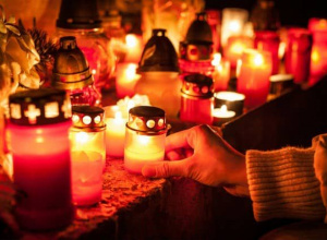 Zapalone znicze ustawione na kamiennej powierzchni.