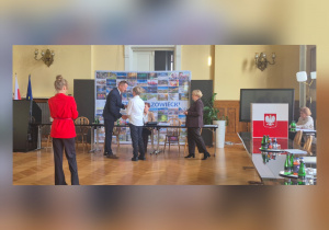 Uczeń odbiera z rąk Zastępcy Dyrektora Wydziału Edukacji, Kultury i Sportu dokument potwierdzający jego nominację na młodzieżowego radnego.