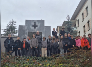 Uczniowie stoją pod pomnikiem upamiętniającym żołnierzy podziemia.