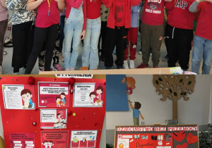 Uczniowie ubrani na czerwono tworzą z dłoni kształt serca, wyrażając solidarność i wsparcie dla idei „Dzieciństwa bez przemocy”. Tablice „Dzieciństwa bez przemocy” przedstawiają kolorowe prace uczniów.