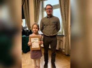 Nagrodzona uczennica trzyma w ręku dyplom.