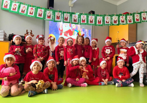 Dzieci ubrane w czerwone, świąteczne stroje i czapki Mikołaja.