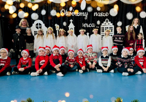 Uczniowie klasy III b, występujący w jasełkach, stoją na tle dekoracji „Otwórzmy nasze serca…”.