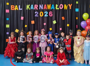 Dzieci w kolorowych przebraniach pozujących przed dekoracją z napisem „Bal Karnawałowy 2026” i motywem LEGO.