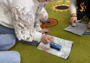 Przedszkolaki bawią się samochodzikami.