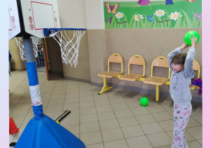 Dziewczynka rzuca piłkę do kosza.