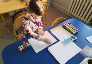 Chłopiec stempluje na kartce cyfry.