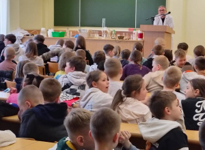 Uczniowie uczestniczą w zajęciach na auli uniwersyteckiej podczas wykładu „Pokazy chemiczne na żywo”.