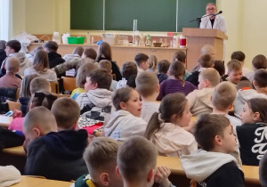 Uczniowie uczestniczą w zajęciach na auli uniwersyteckiej podczas wykładu „Pokazy chemiczne na żywo”.