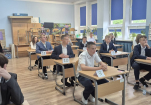 Uczniowie klasy VIII b, zgromadzeni w sali lekcyjnej, z pełnym skupieniem i gotowością oczekują na rozpoczęcie egzaminu ósmoklasisty