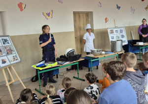Uczniowie z zainteresowaniem słuchają gości podczas II Festiwalu Zawodów, poznając tajniki pracy policjanta, kucharza i stylistki paznokci.