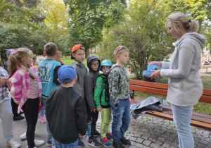 Pani rozdaje uczniom rękawiczki ochronne