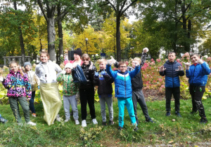 Uczniowie klasy V b w parku podczas zbierania odpadów.