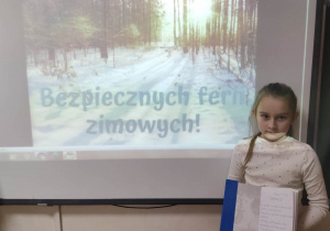 Uczennica klasy II a trzyma zeszyt z zapisanymi zasadami bezpiecznego zachowania